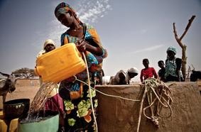 Woman in an arid region collecting water, illustrating global water scarcity challenges